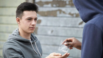 man handing other man bag of fentanyl pills