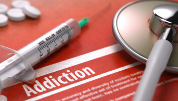 stethoscope and needle laying on table next to pills